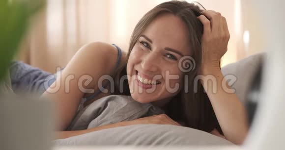 穿着睡衣躺在床上的快乐女人视频的预览图