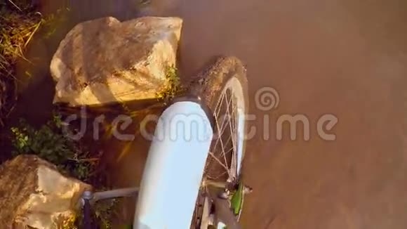 骑自行车的人骑着自行车穿过一条泥泞的小溪靠近前轮视频的预览图