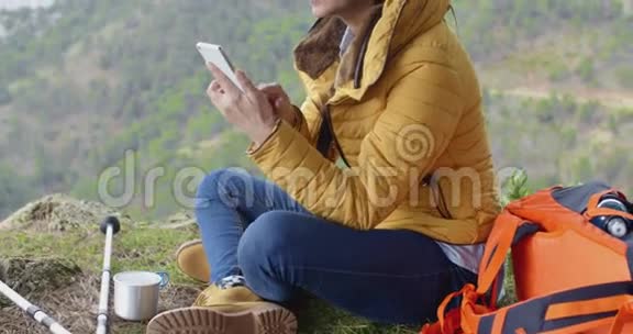 微笑的女徒步旅行者使用她的手机视频的预览图