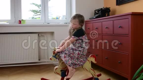 可爱的小女孩在摇摆的马上摇摆小女孩穿花裙子儿童概念视频的预览图