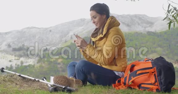 微笑的女徒步旅行者使用她的手机视频的预览图