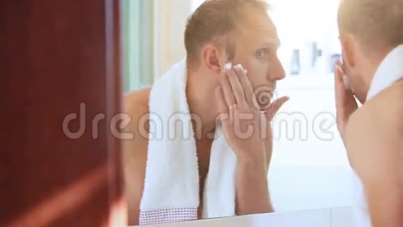 清晨普通浴室场景年轻的成年男子在刮胡子前用脚踩脸视频的预览图
