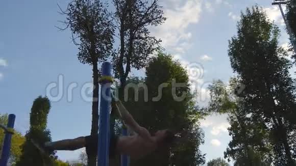 在城市公园的水平杆上做体操的运动员男运动员在比赛期间进行力量练习视频的预览图