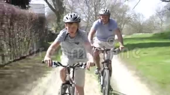 父亲和儿子骑自行车沿着乡间小路视频的预览图