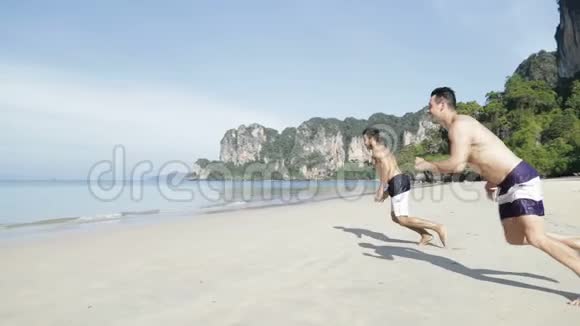两人在沙滩上水中奔跑年轻的男性夫妇在海上度假游客视频的预览图