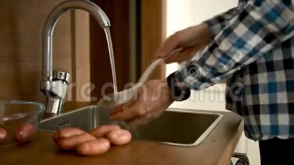 男人在厨房的水槽里洗土豆视频的预览图