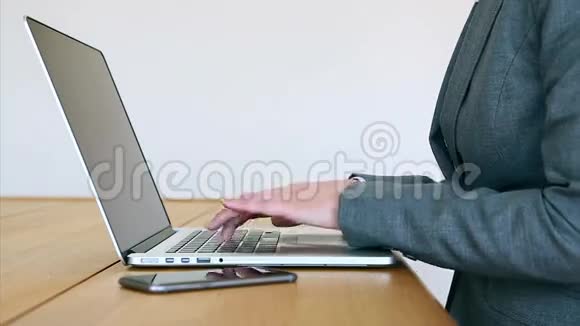 女商人在办公桌上使用笔记本电脑和智能手机视频的预览图