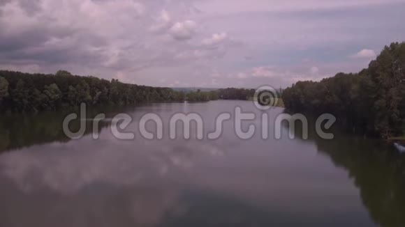 空中观景在阳光明媚的夏日早晨低空飞越湖面绿树和小山湖面上云的倒影视频的预览图
