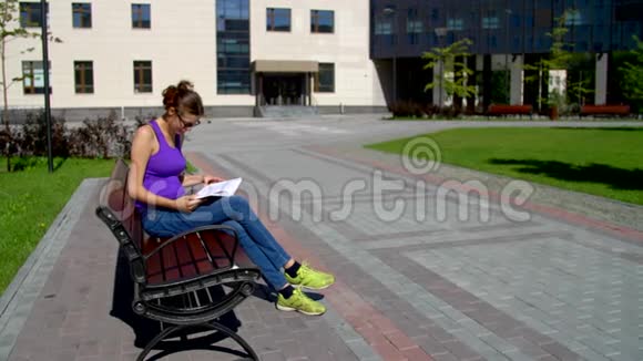 一个戴眼镜的女孩坐在长凳上看书视频的预览图