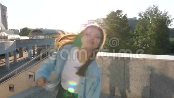 一个棕色头发的女孩长发在夕阳的背景下在城市里跳舞视频的预览图
