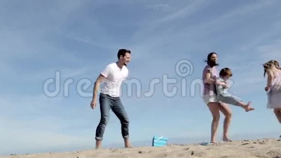 母亲和父亲在海滩上旋转他们的儿子和女儿视频的预览图