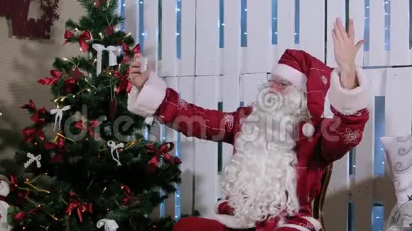 圣诞老人坐着让自拍成为他的智能手机视频的预览图