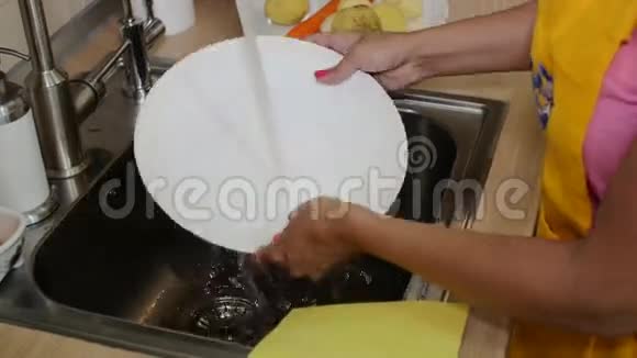 漂亮的女人在厨房水槽里洗盘子视频的预览图