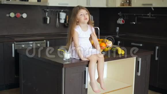 坐在厨房桌子上的小女孩视频的预览图