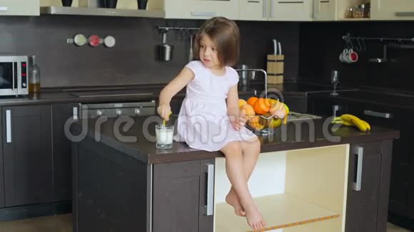 坐在厨房桌子上的小女孩视频的预览图