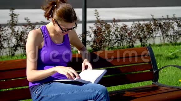 一个戴眼镜的女孩坐在长凳上看书视频的预览图