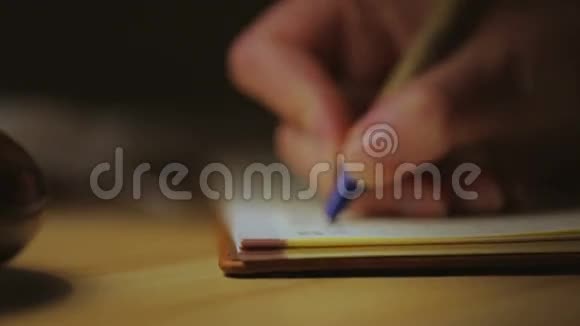 一个女人写在笔记本上坐在灯旁特写镜头视频的预览图