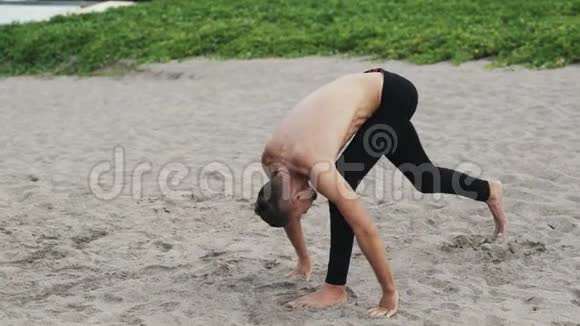 年轻的运动员在海滩上练习瑜伽视频的预览图