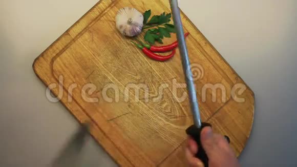男人的手在一个古老的木制烹饪板的背景下磨刀视频的预览图
