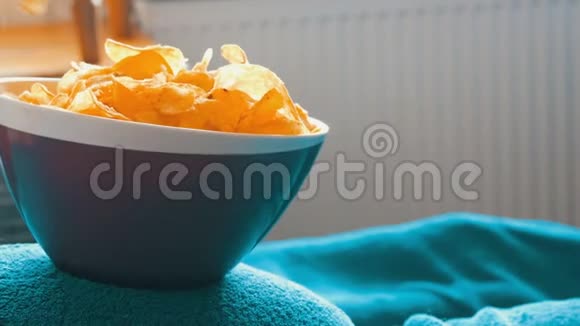 已婚夫妇躺在一张蓝色毯子下面的沙发上吃着站在一个大肚子上的盘子里的薯片视频的预览图