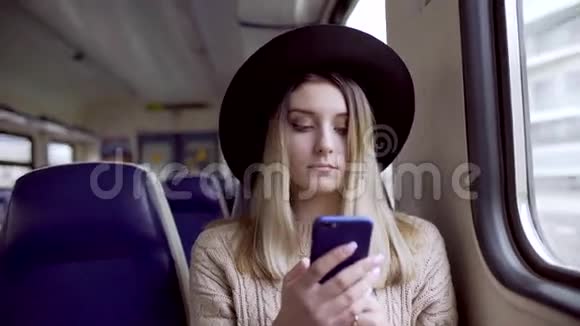 年轻女子在手机上打字微笑着坐在火车上视频的预览图