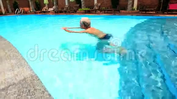 有胡子的老人在游泳池里用棕榈砖围墙游泳视频的预览图