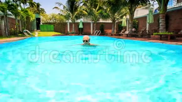 有胡子的老人在游泳池里用棕榈砖围墙游泳视频的预览图