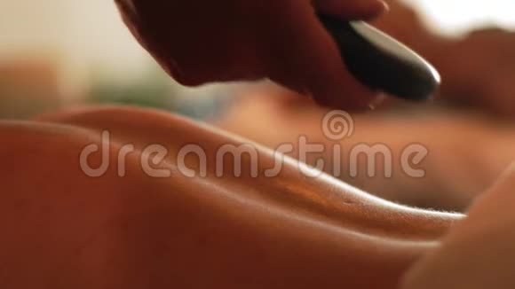年轻女子在美容水疗中心接受石头按摩水疗和身体按摩护肤理念放松和视频的预览图