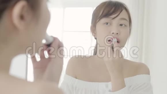 美丽的肖像年轻的亚洲女人在镜子上涂抹和看化妆口红视频的预览图
