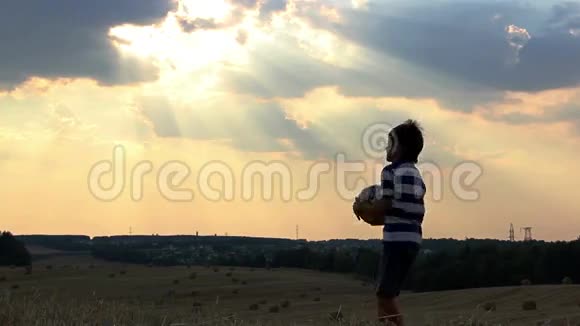 男孩在日落时分在球场上打球男孩梦想成为一名足球运动员视频的预览图