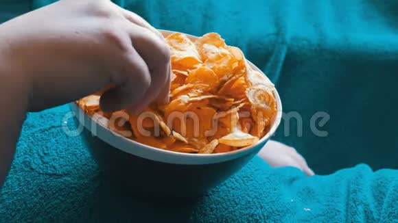 已婚夫妇躺在一张蓝色毯子下面的沙发上吃着站在一个大肚子上的盘子里的薯片视频的预览图