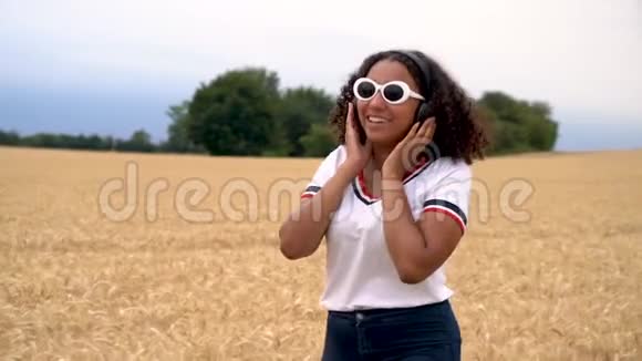 非洲裔美国少女少女少女走在田野里用无线耳机听音乐视频的预览图