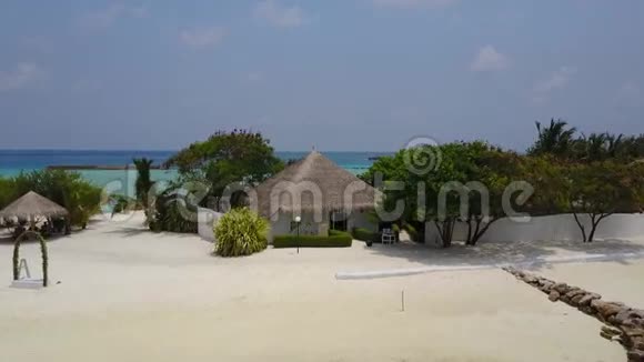 带白色沙滩棕榈树和绿松石印度洋的热带岛屿度假酒店的水疗平房的鸟瞰图视频的预览图