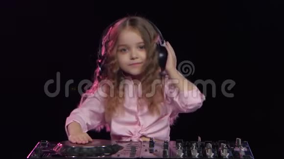 戴耳机的小女孩为DJ控制台播放黑色背景视频的预览图