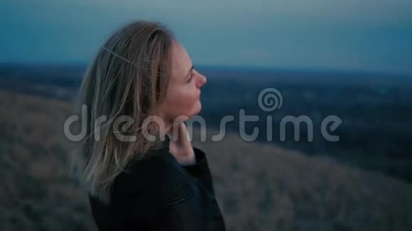 美丽的女孩看着夕阳和微笑头发在风中视频的预览图