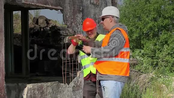 建筑工人在损坏的建筑物附近交谈视频的预览图