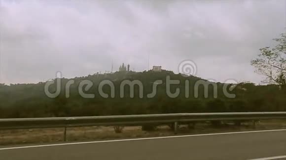 从高速公路上看到满是绿色树木和植物的山脉另一边的城堡旅程视频的预览图
