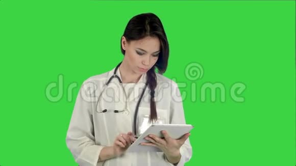 漂亮的女医生用平板电脑在绿色屏幕上做听诊器Chroma键视频的预览图