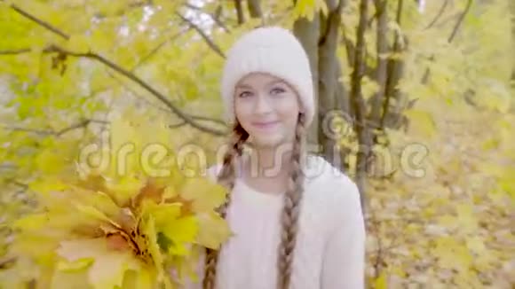 秋天的森林里美丽的女孩带着黄色的枫香微笑视频的预览图
