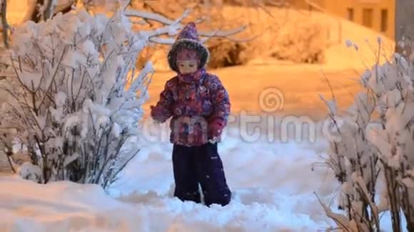 快乐美丽的小女孩在冬天扔雪夜晚照明视频的预览图