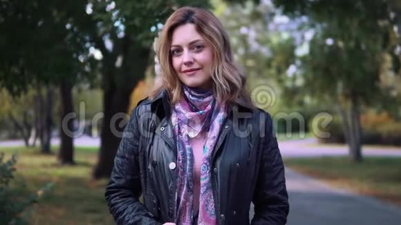 秋天公园迷人年轻女子的特写肖像穿夹克和围巾的女孩视频的预览图