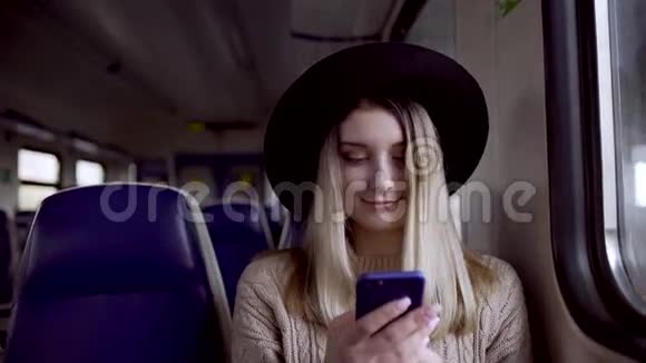 年轻女子在手机上打字微笑着坐在火车上视频的预览图