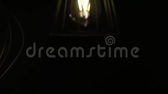 灯泡自然地在电线上移动灯在黑色背景上摆动慢动作视频的预览图