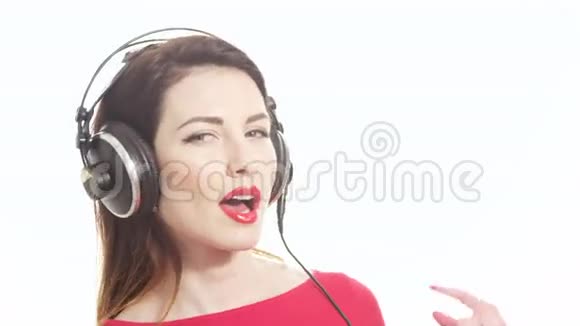 可爱的红色女孩听着大耳机里的音乐跳舞玩得很开心把红色口红涂在白色上视频的预览图