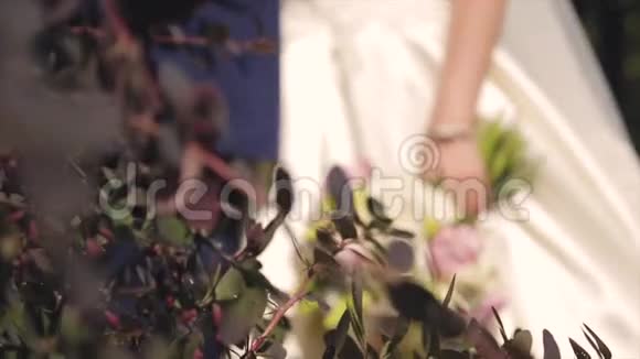新娘和新郎捧着一束鲜花拥抱一束婚礼花束和双手特写视频的预览图