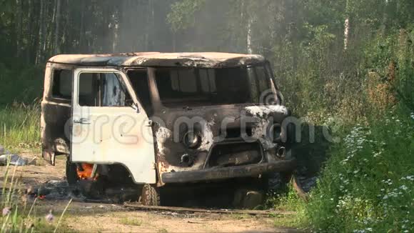 一辆燃烧着的老汽车在空旷的夏天散发着烟雾视频的预览图