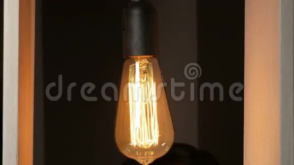 年轻人把爱迪生灯泡拧在灯设计师身上老式灯长丝美丽的温暖光线视频的预览图