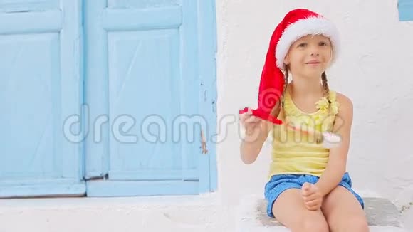 在Mykonos的圣诞假期在老街上戴圣诞帽的小女孩典型希腊人街上的孩子视频的预览图