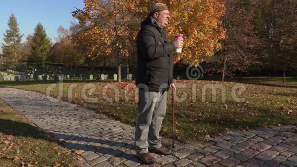 带着拐杖和咖啡的残疾人在墓地的路上视频的预览图