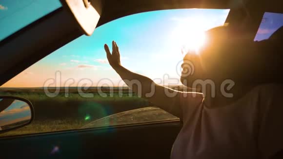 女孩挥手在窗户阳光下风在汽车慢动作视频年轻快乐的女孩开汽车视频的预览图